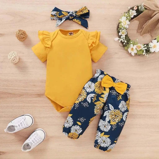 Newborn baby girls' clothing set with yellow short sleeve bodysuit, floral navy pants with yellow bow, and matching headband.