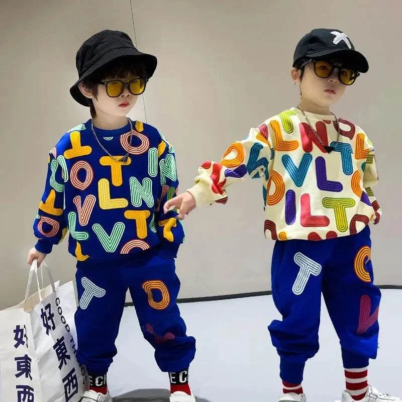 Two boys wearing colorful autumn cotton letter print pullover sweatshirts and matching blue sweatpants children's clothes set, accessorized with black hats and sunglasses.