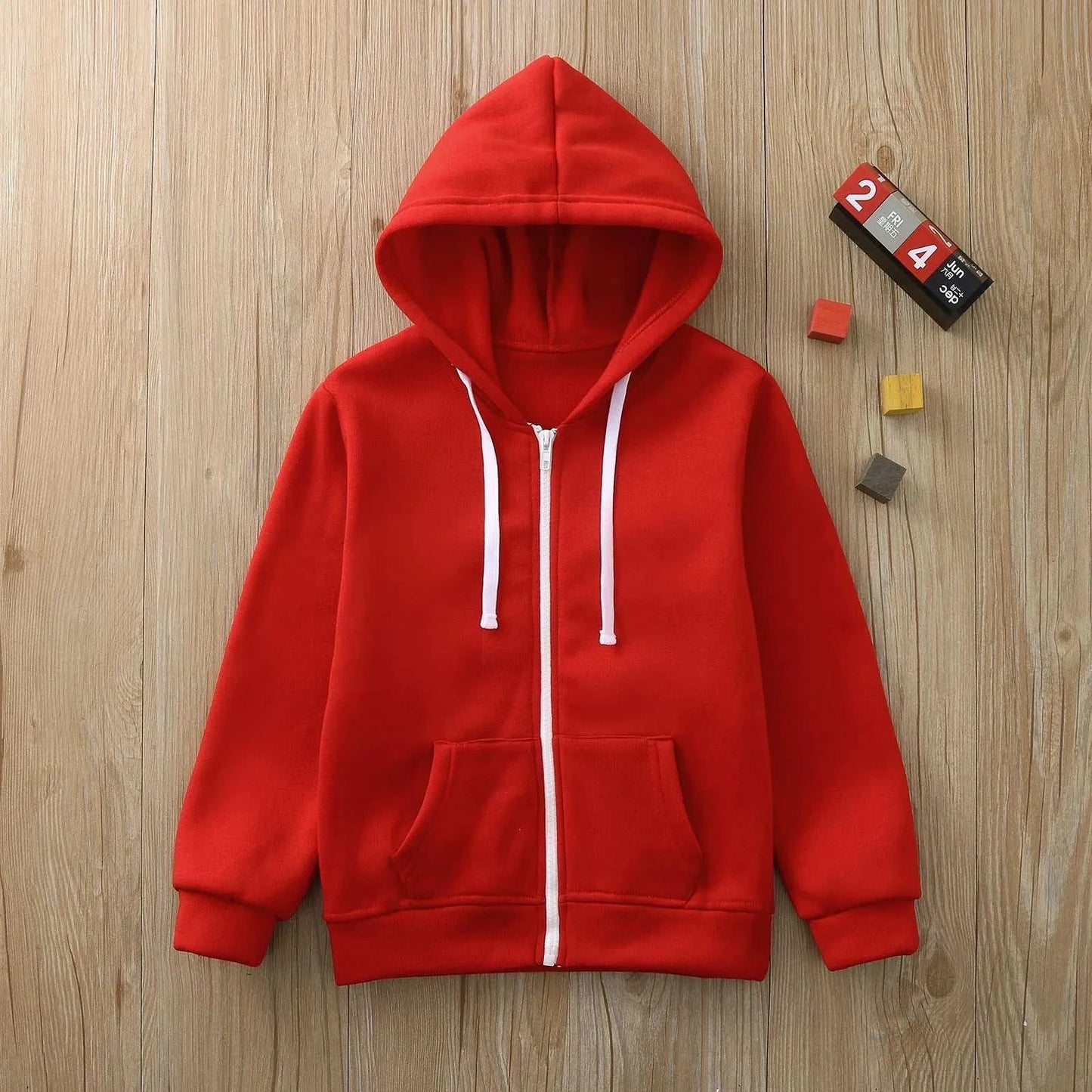 Kids red wind proof jacket zip sweatshirt hoodie with long sleeves and front pockets on wooden background